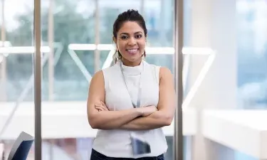 Confident healthcare administrator standing in a modern office environment with arms crossed, demonstrating leadership and professionalism.